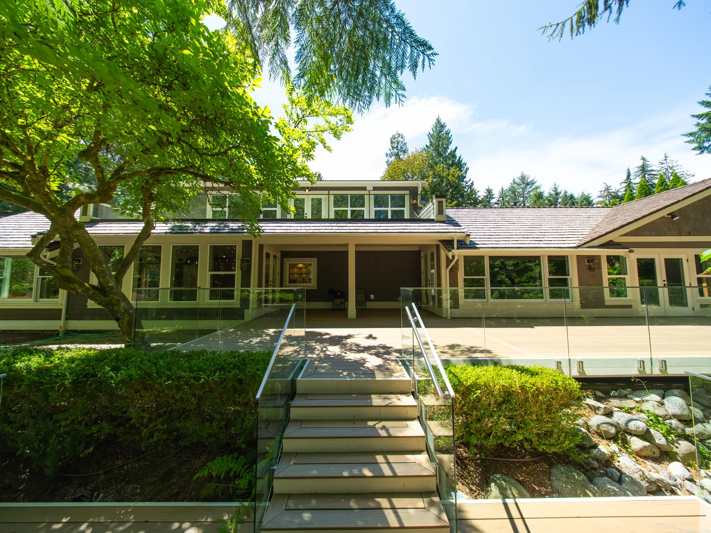 Rear exterior with covered porch and stone steps under mature trees
