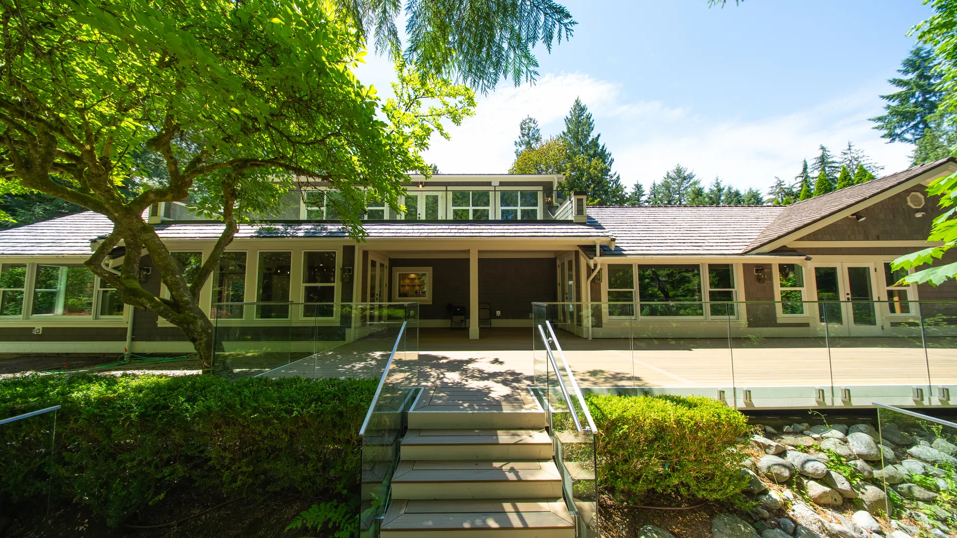 Rear exterior with covered porch and stone steps under mature trees