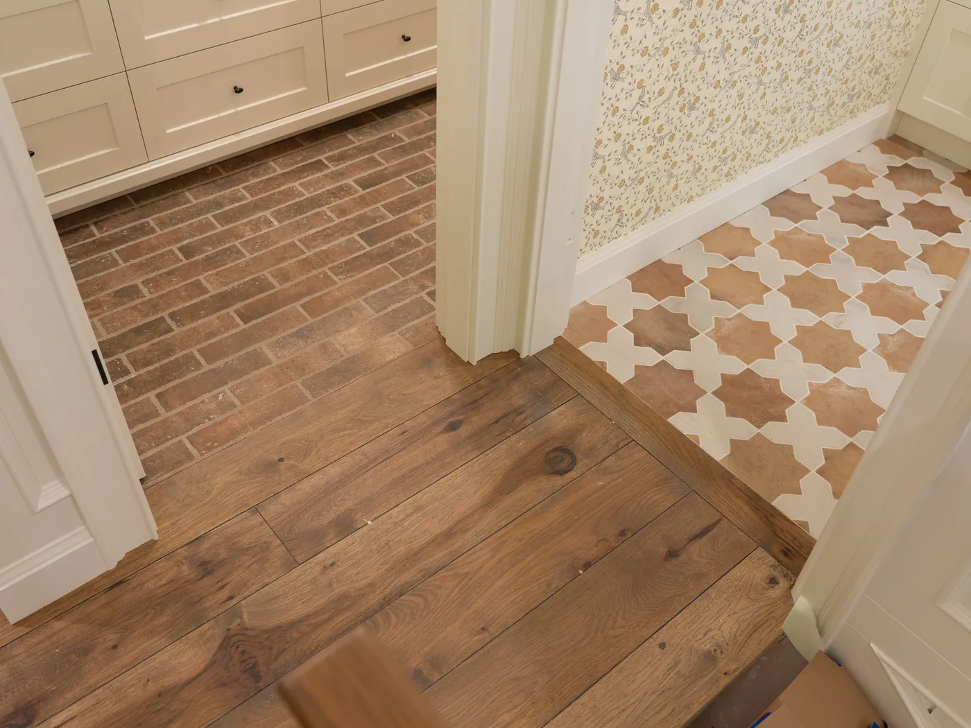 Brick-look tile transitioning to oak flooring at a doorway